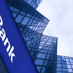 Niebieski szyld z napisem "Bank" na tle nowoczesnych, szklanych wieżowców. Czy to bank z 1600 roku?