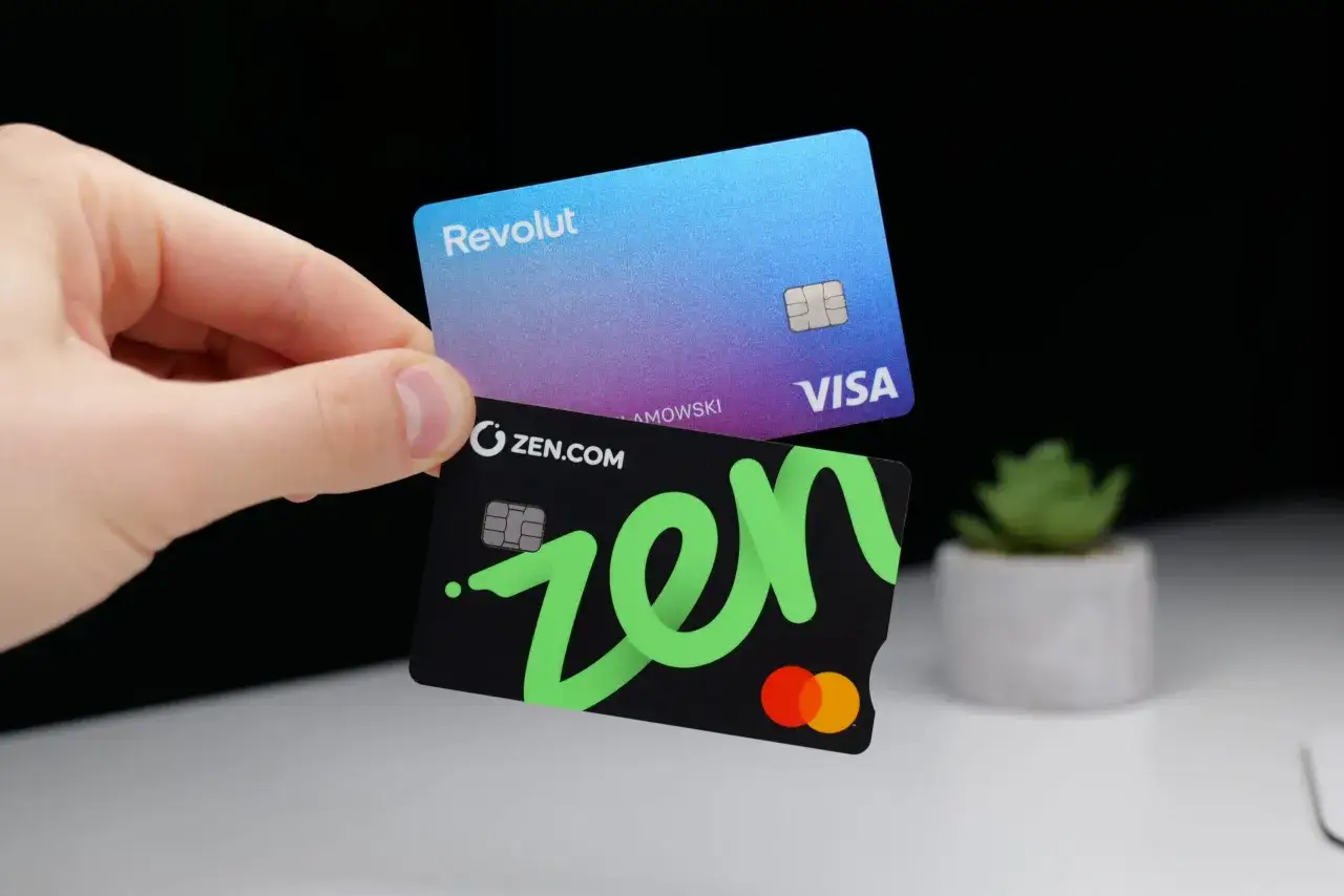 Dłoń trzyma dwie karty: Revolut i czarną z zielonym logo zen.com. To pytanie o zen com co to?